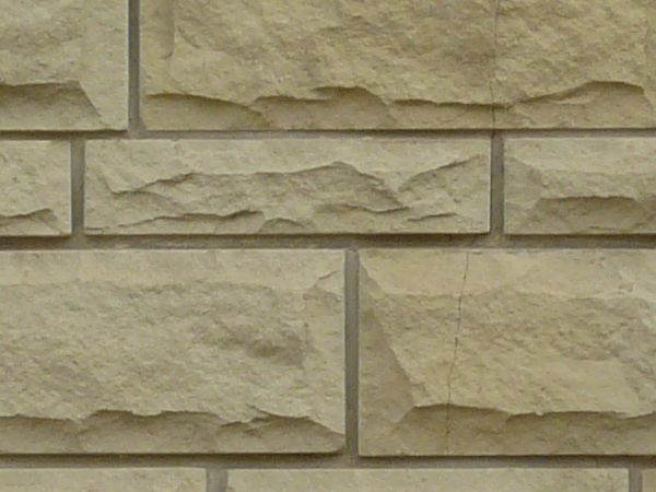 Straight beige stone in different sizes set evenly in wall.